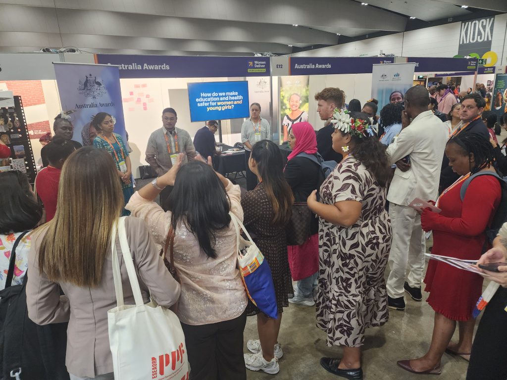 Participants and the public gather around the Australia Awards booth to listen to the scholar panel. 