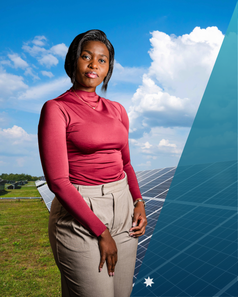 Nomathemba wears a pink top and beige pants with solar panels, green grass and a partially cloudy sky behind her. 